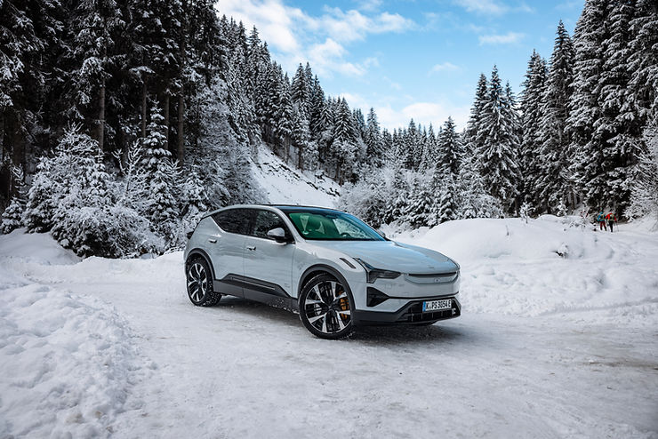 SUV steht auf verschneiter Straße vor verschneitem Wald mit Nadelbäumen