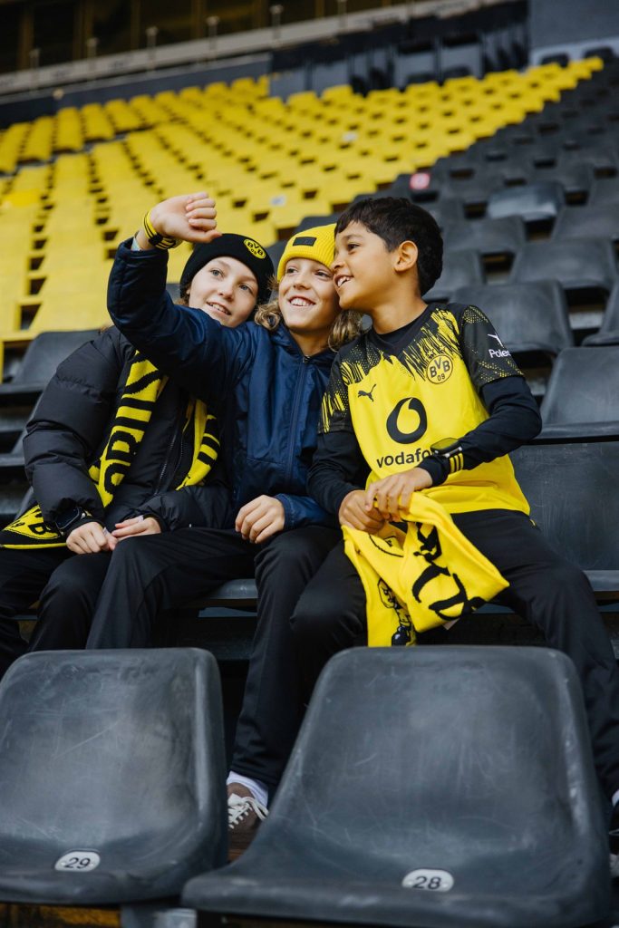 Drei Kinder mit Xplora X6Play BVB-Edition machen ein Foto auf der Stadiontribüne